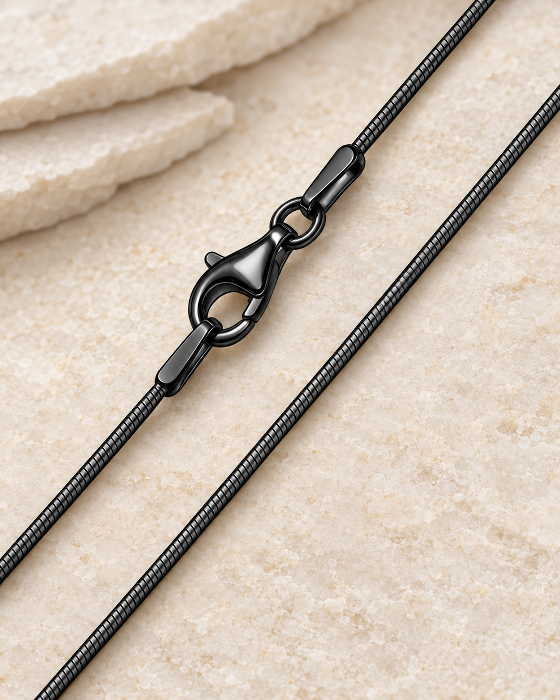 30 inch black premium snake chain with lobster clasp on cream stone.