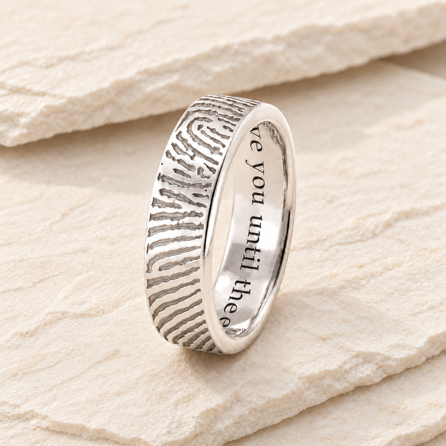 Silver fingerprint band with unfilled metal engraving on cream stone.