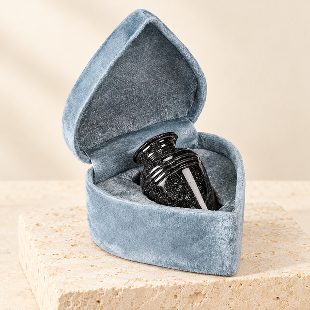 black grain marble keepsake urn on a cream limestone background