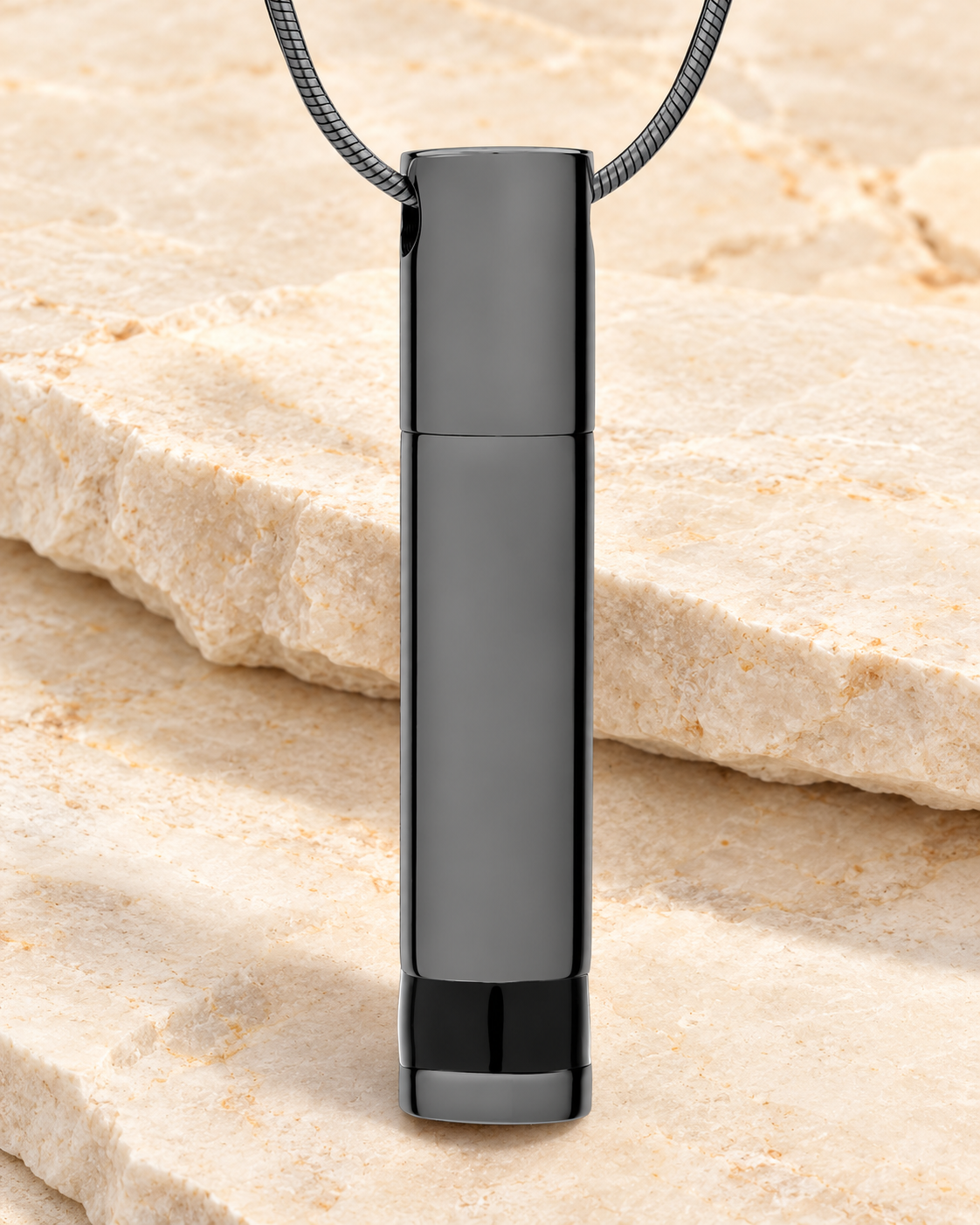 Forever Collection Black Plated Hero Cremation Necklace on a cream stacked-stone background