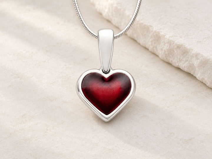 Silver red ash-resin heart on a cream stone background