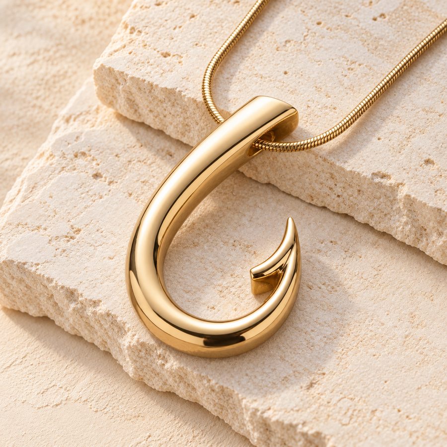 Gold fishhook memorial necklace on cream stone.
